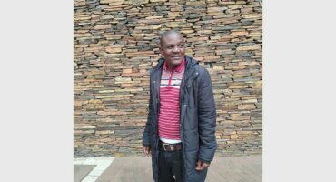 Man in front of a stone wall.