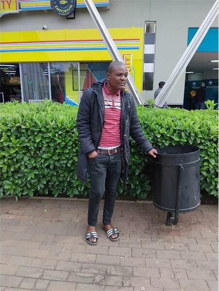 A man stand s in front of a hedge.