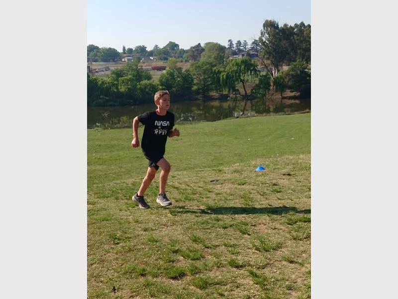 A boy runs over grass.