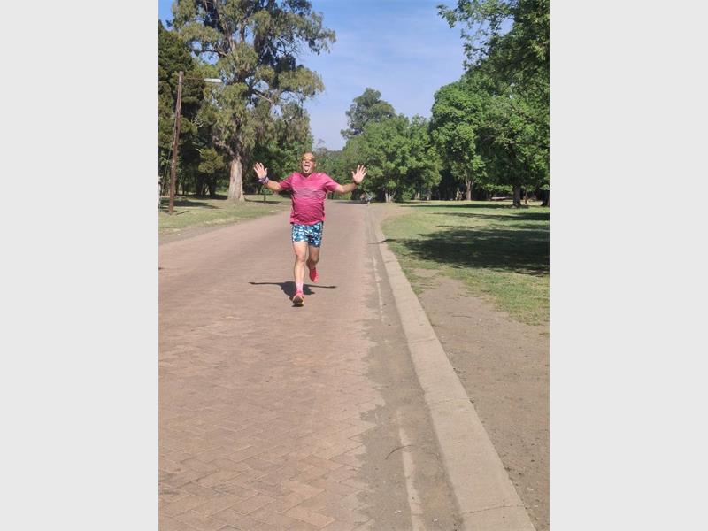 Man with a pink T shirt jogs in the park.