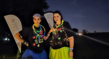 Two women with glow sticks and neon clothes.