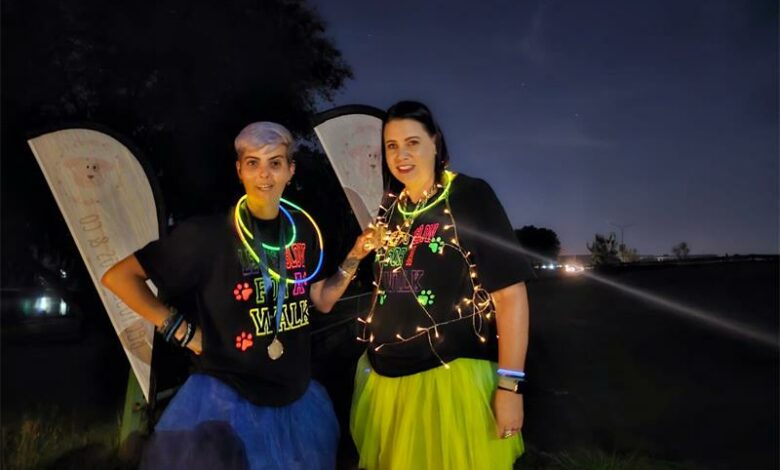 Two women with glow sticks and neon clothes.