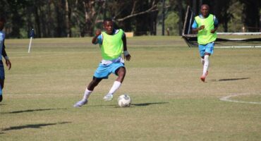 a soccer player dribbles the ball