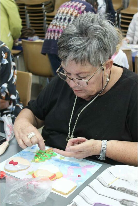 woman decorates Christmas tree cookie
