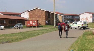 Two learners walk towards apartment buildings