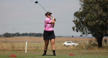 Woman tees off in golf.