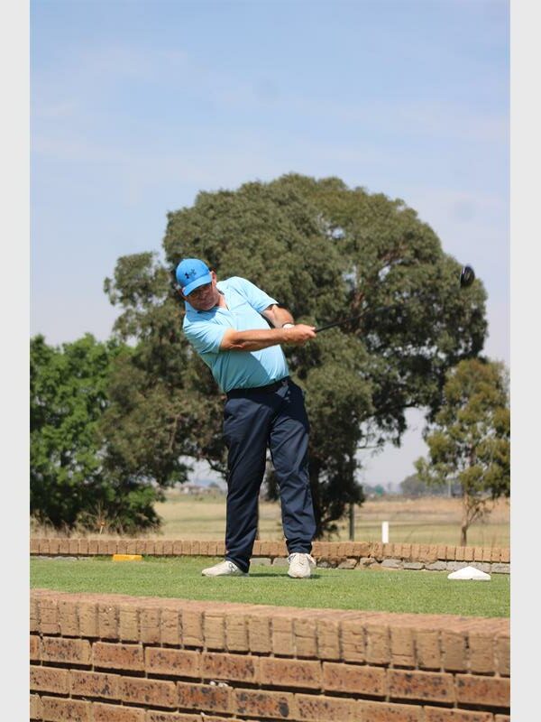 Golf player in light blue shirt tees off