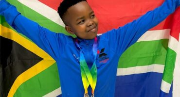 Boy with medals holds up SA flag