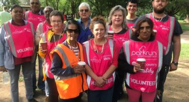 A group of people of whom most are wearing pink bibs.