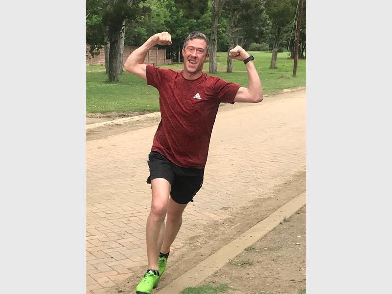 Man in maroon shirt shows his muscles while running