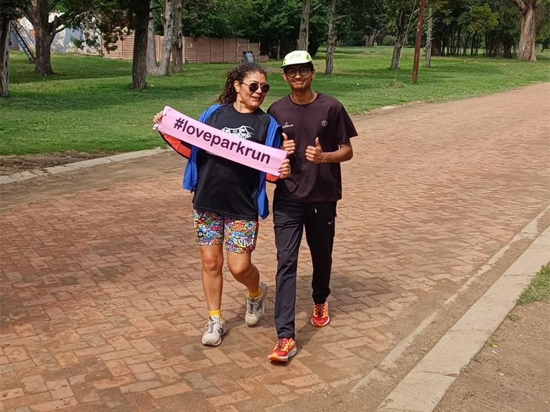 Woman and man with a pink banner banner I love parkrun