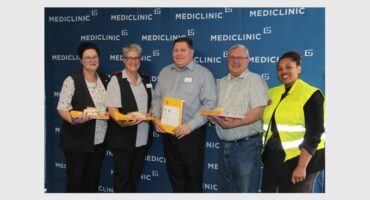 five people with colouring books standing in front of a banner of Mediclinic
