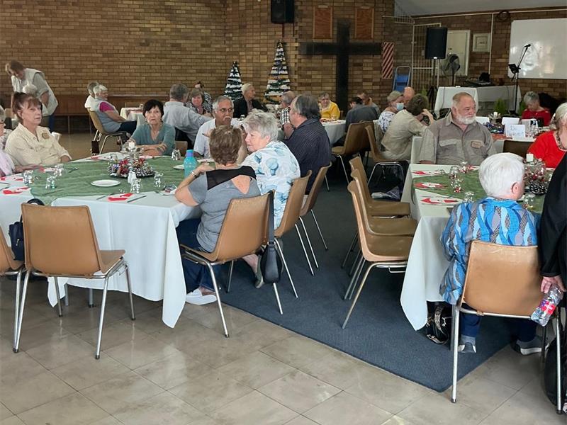 people sit around tables in a big hall