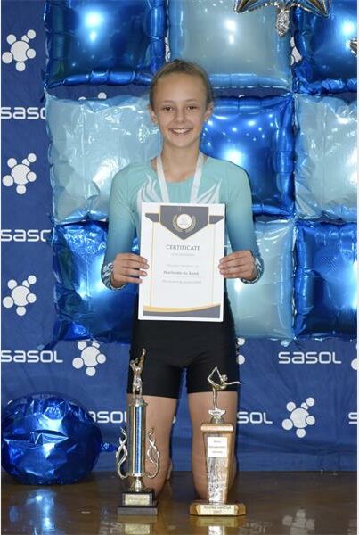 Girl holds up certificate and trophies with blue background.