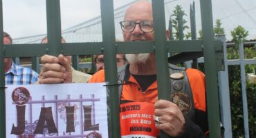 man with orange shirt behind pallissades