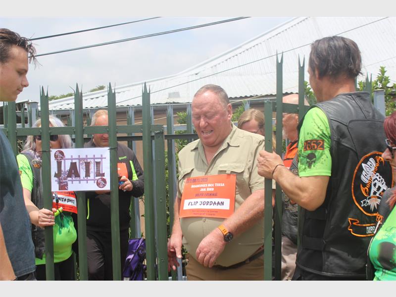 Man in khaki and with a sign around his neck walks through a gate