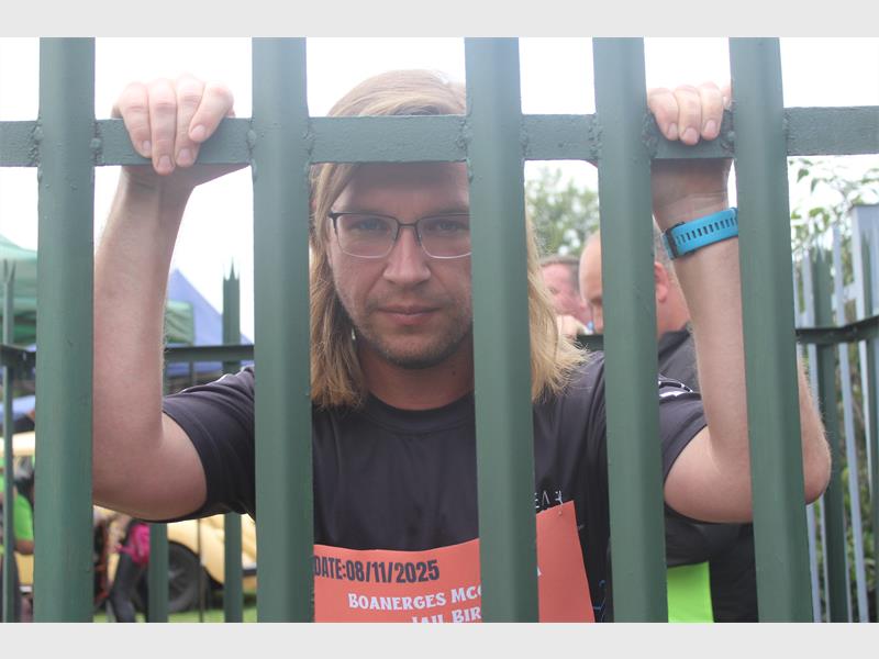 Young man with long hair looks through palisades.