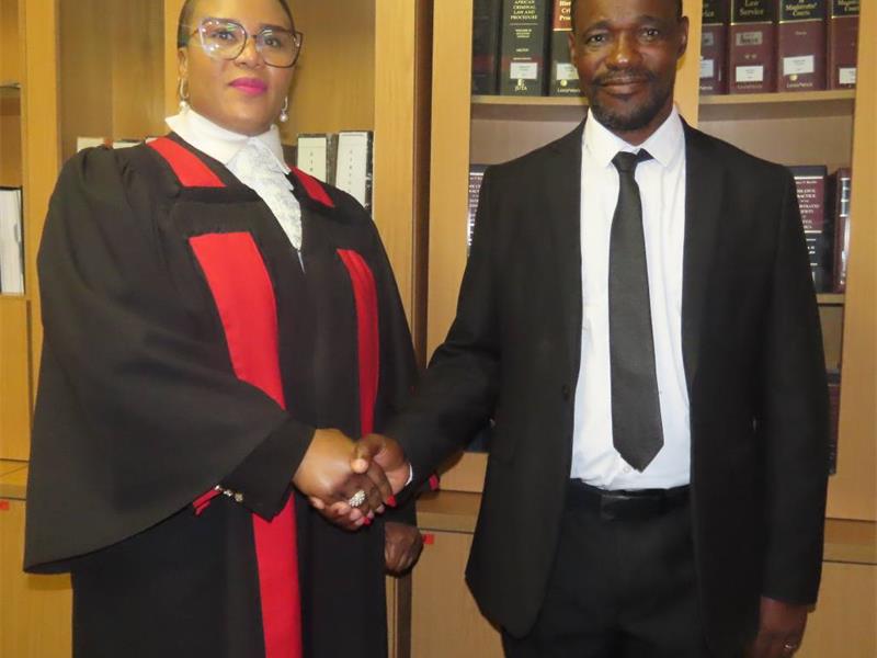 magistrate shakes hands with a man in suit.
