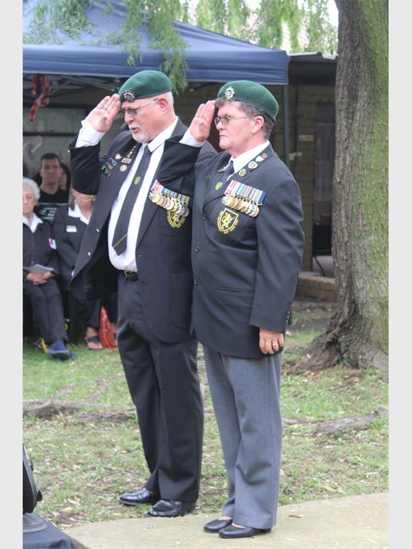 two people in military regalia salute.