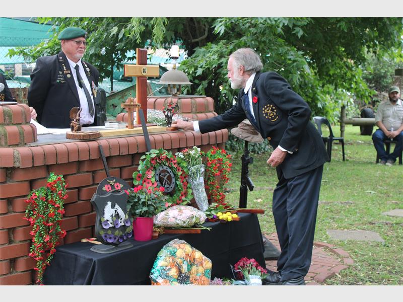 elderly man lays a wreath