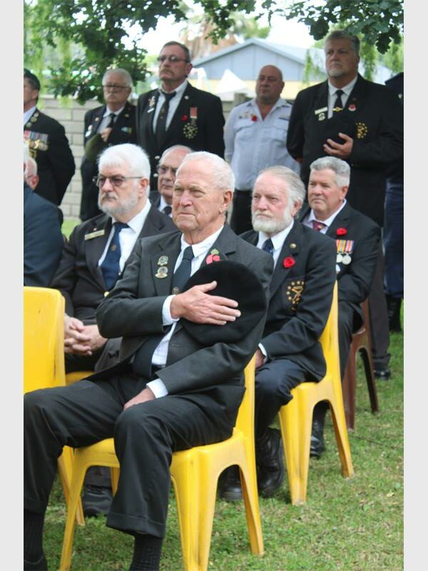 veterans wearing red poppies with their hands on their hearts