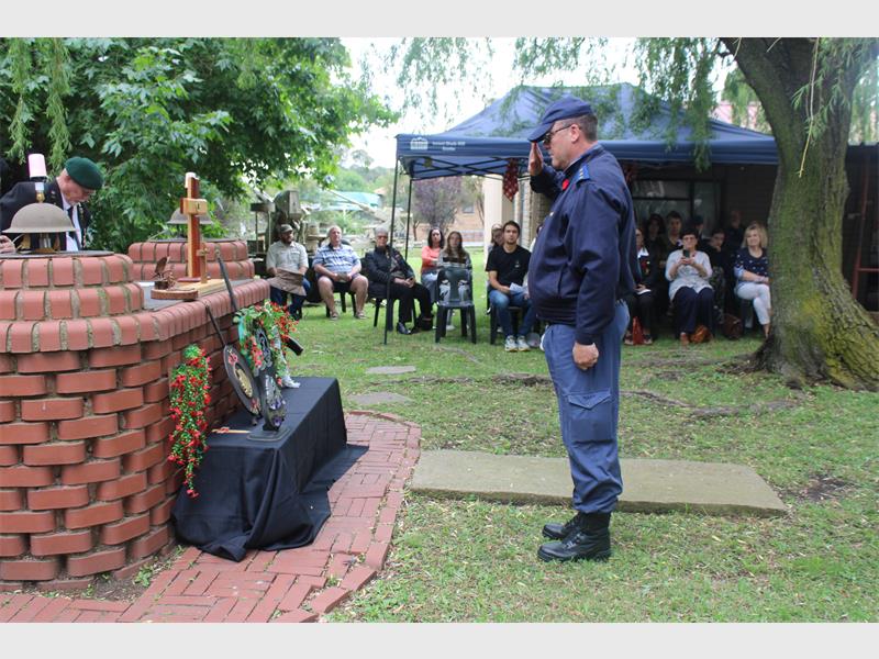 a policeman salutes in front of the wreaths