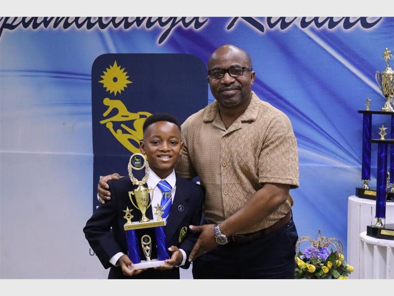 Boy with trophy next to his coach