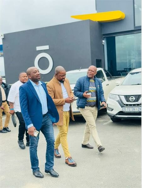 men in suits walk in a parking area