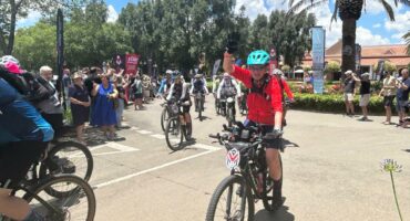 Cyclists preparing for a ride at Ridge Times community event, sunny day with lush greenery.