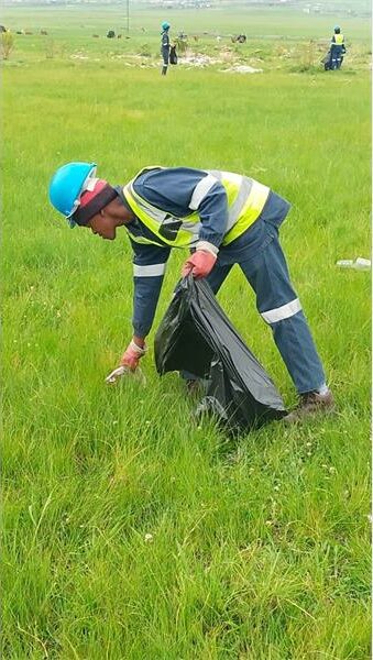 a man picks up rubbish in the veld