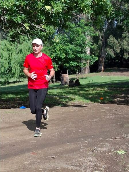 Man in red shirt runs on dirt road