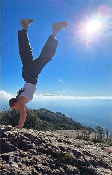 girl does a handstand on rugged terrain