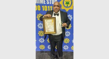 a man with a certificate in front of a police banner