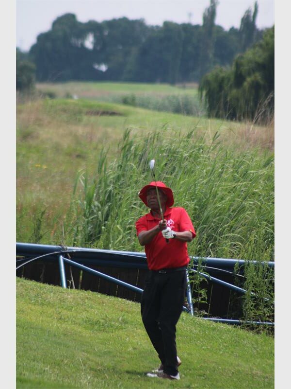 Man in a red shirt hits a golf ball