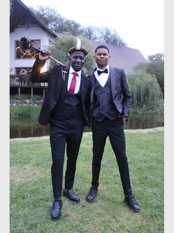 two young men in suits and an African head piece