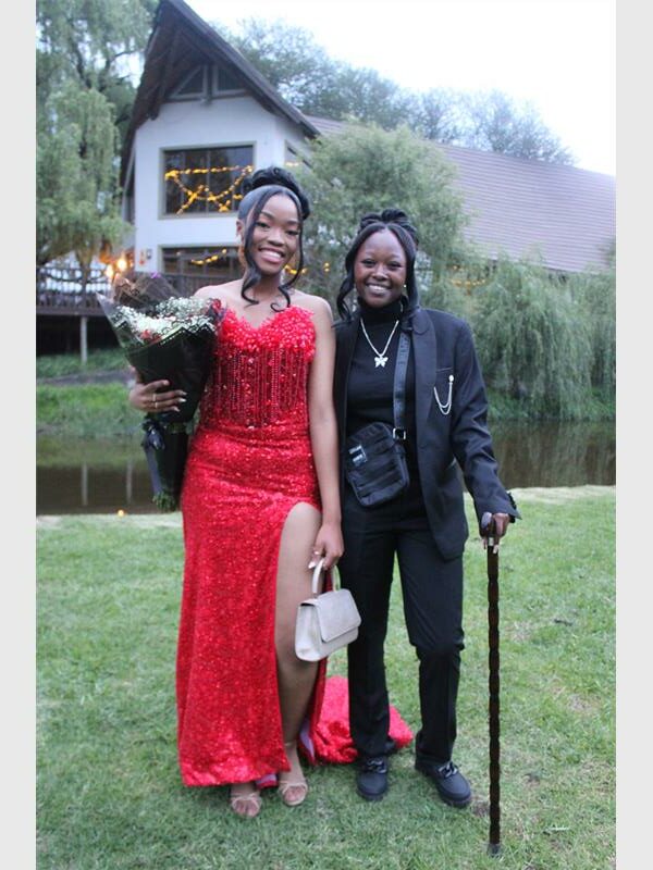 girl in red dress holding flowers and girl in suit with cane