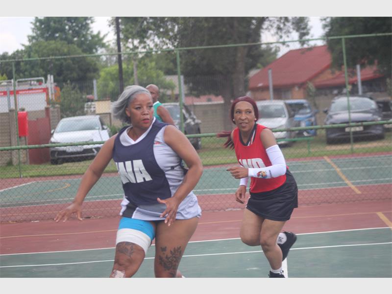 Netball players chase after the ball.