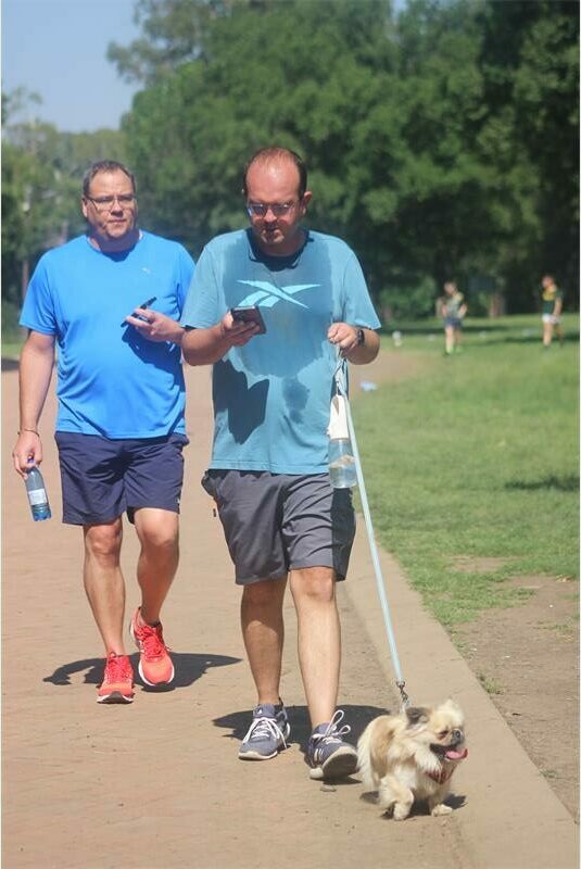 Two men in blue shirts with a dog