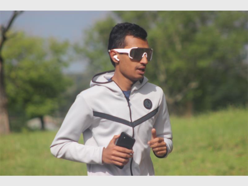 young man with sunglasses runs outdoors