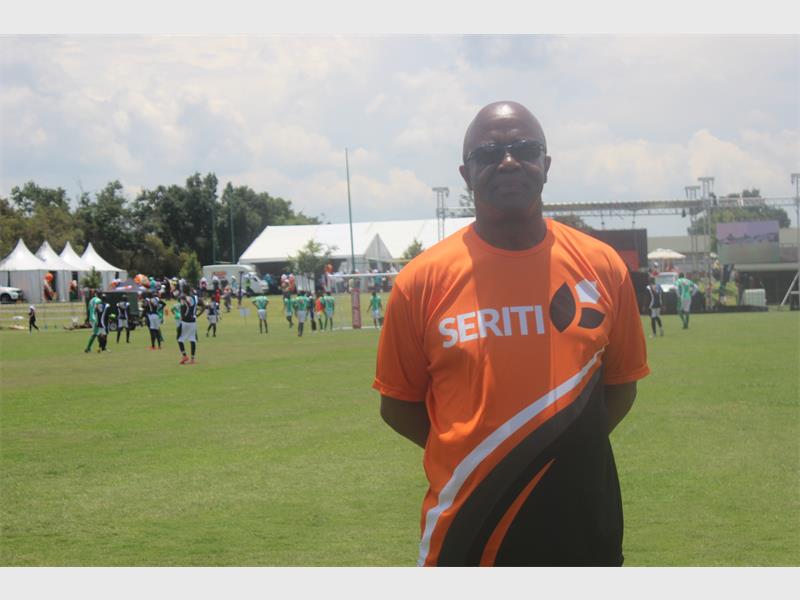 man in orange shirt with soccer game in background