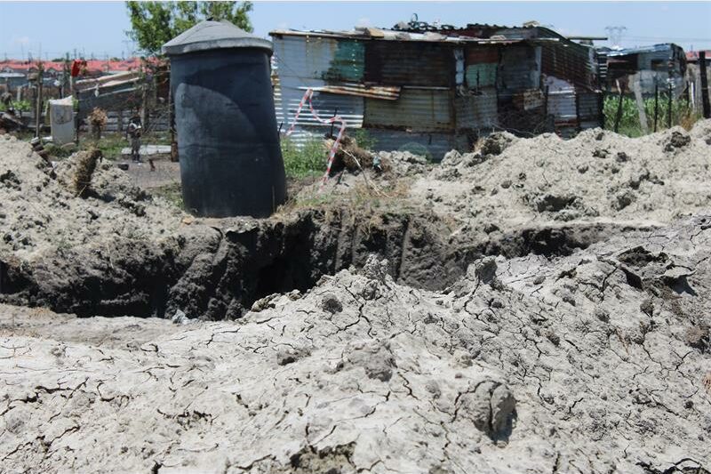 a muddy pit with an outside toilet