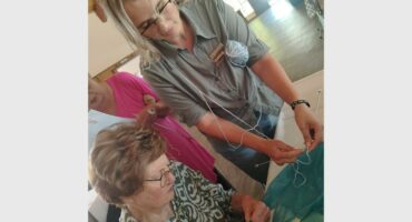 woman shows another a knitting pattern