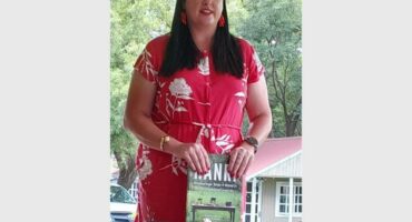 woman with a dark ping shirt holds onto a book