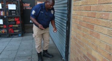 Man closes window gates of shop
