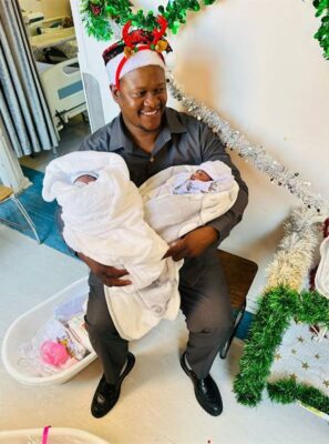 man with Christmas hat holds two babies