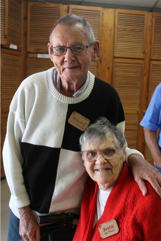 a man wearing a black and white jersey is standing by a woman wearing a red jacket