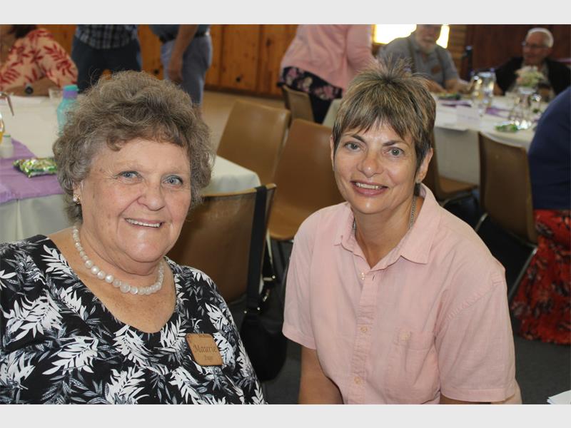 woman dressed in black and white sits next to a woman in pink