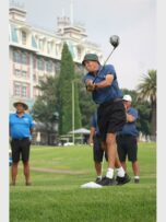 golfers look on as elderly man hits the ball