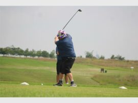 man in navy coloured shirt plays golf