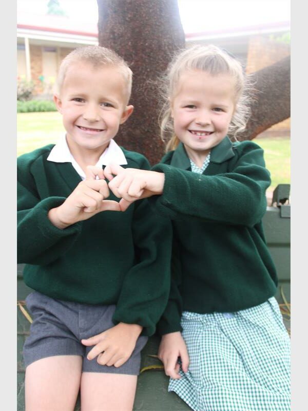 twin boy and girl sign a heart with their hands